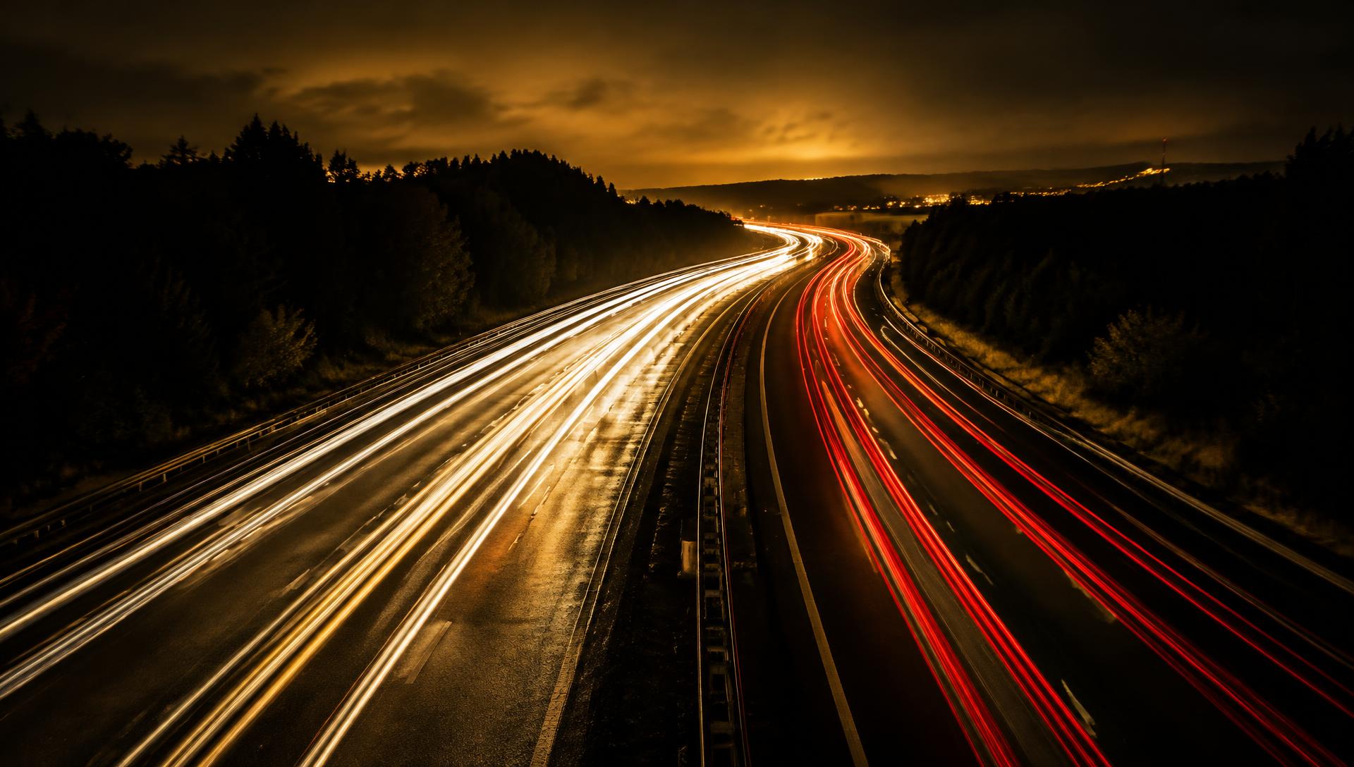 Rodovia à noite com rastros de luz dos faróis